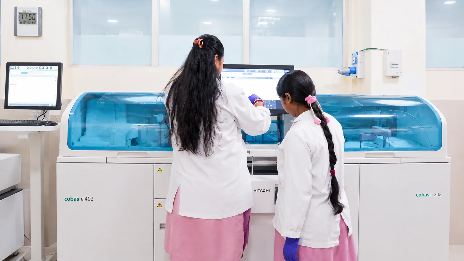 Two technologists working at the laboratory analysers